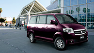 a-purple-APV-parked-in-front-of-a-mirror-building