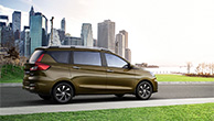 Sideshot-Khaki-Suzuki-Ertiga-with-city-buildings-in-the-background