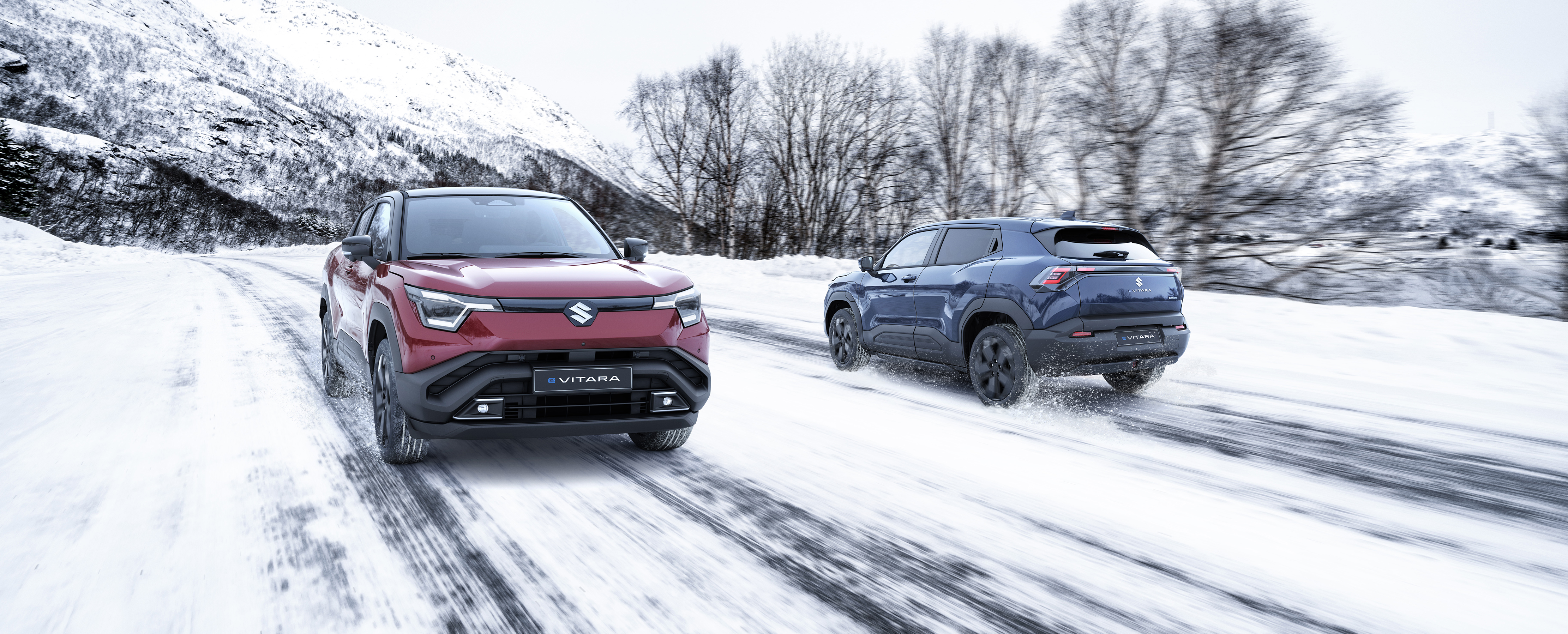 two-suzuki-e-vitara-vehicles-driving-on-a-snow-covered-road-in-a-winter-mountain-landscape